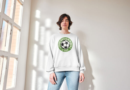 Mockup of woman wearing sweatshirt with customizable color by window, low angle