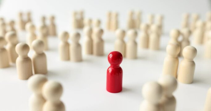 Red figure stands out from crowd with white figures on surface of wooden table. Leadership in modern society and special person