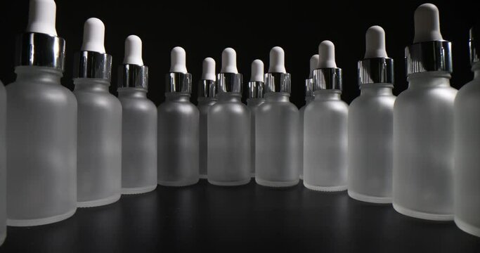 Row of empty glass cosmetic bottles on gray background. Glassware for essential oils and facial serum in dermatological lab