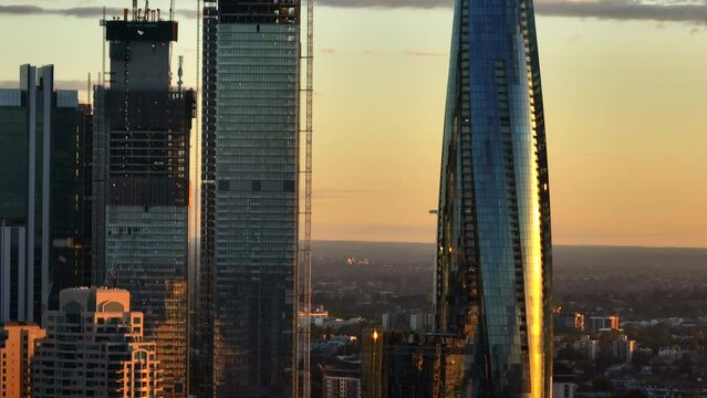 Airplane approaching Sydney airport behind the ultra modern skyscrapers in the city at sunset. Drone lifting shot