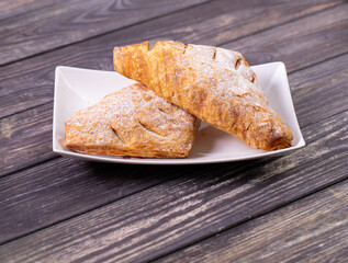 Triangular puff pastry buns with fruit filling on a white plate. puff pastry fresh on a wooden table