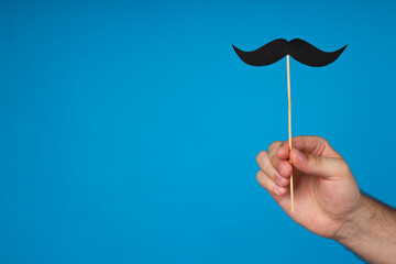 Black, paper mustache in a man's hand