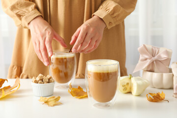 Pumpkin coffee, leaves, gift box and female hands on white background