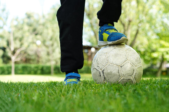Legs of boy soccer player, bottom view. Ball on the grass. Young athlete on a green meadow