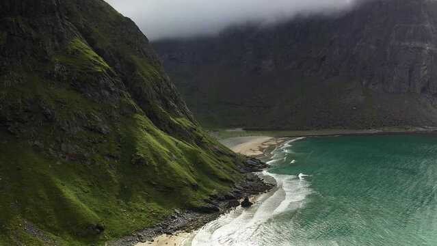 Revealing aerial shot of the isolated Kvalvika Beach in the Lofoten Islands Norway, cinematic drone shot with turquoise blue water