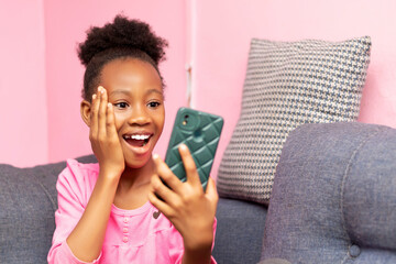 young African little girl holding a cell phone in her hands