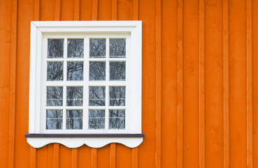 Wooden window background. Rustic cottage house wall. White wood window frame. Countryside architecture texture. Vibrant color orange paint. Scandinavian style architecture.