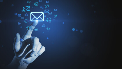 Close up of man hand pointing at glowing email letter icons on dark blue background with mock up place. Communication and business message concept. - obrazy, fototapety, plakaty