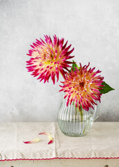 Beautiful bouquet of purple, orange yellow cactus dahlia flower in a glass vase. Romantic minimal...