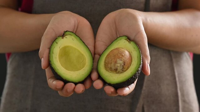 Half ripe hass avocado fruit in hand