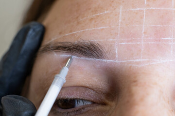 Zoomed-in capture of a meticulous eyebrow mapping process before a woman's permanent makeup session