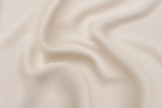 Close-up texture of natural beige or ivory fabric or cloth in brown color. Fabric texture of natural cotton or linen textile material. Beige canvas background.