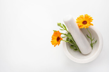 Calendula officinalis flowers in mortar on white background. Marigold medicinal plant, herbal...