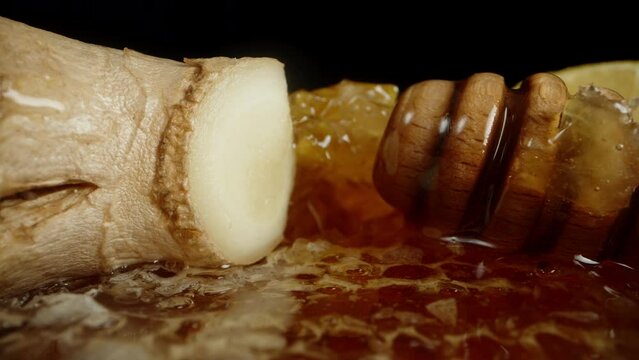 The roots of ginger with lemon are lying on top of the honey in the honeycombs. Dolly slider extreme close-up.