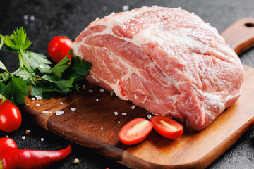 Fresh and raw meat filet neck of pork on wooden board on dark background, steak top view