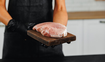 Butcher woman hold fresh meat steak pork on dark background