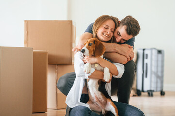 Embracing each other. Young couple with dog are moving to new home