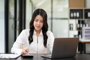 Businesswoman working with tablet and using a calculator to calculate the numbers of static in office. Finance accounting concept.