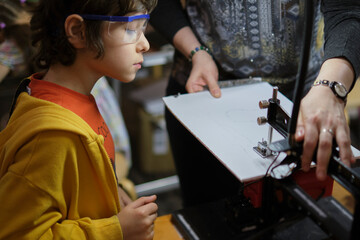 Safety and Skill: A seasoned educator watches closely as a young apprentice learns to operate a...