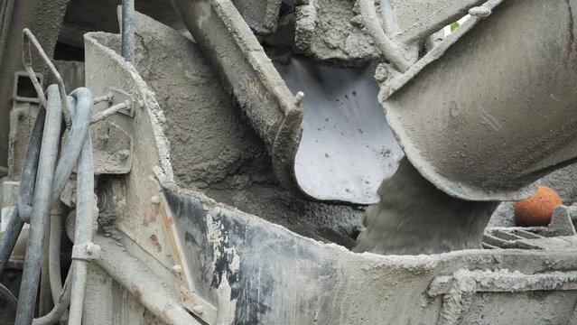 Ready mix concrete transfers wet material to delivery truck chute close up