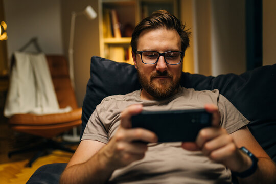 Front view of an adult man playing video game on his phone.
