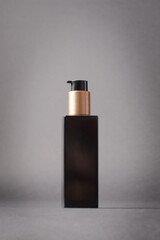 Vertical mockup of dark dispenser product with bronze details studio shot.