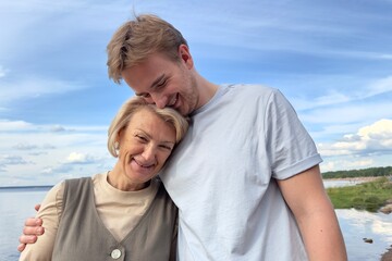 Obraz premium Happy couple or mother with her son walking outdoors on natural sea or lake background 