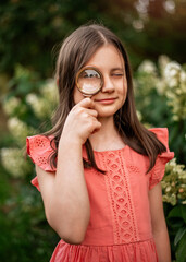 A beautiful girl with a magnifying glass near her face. The concept of searching