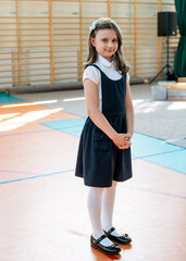 A schoolgirl in a neat school uniform in the school's gym