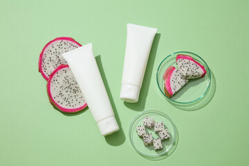 Two blank label tubes placed on green background with white dragon fruit slices. Dragon fruit (Hylocereus) can have a positive impact on your health and well-being