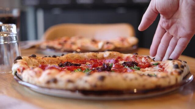 Close up of a person serving a pizza to the table slow motion