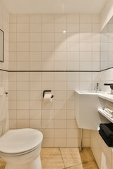 a bathroom with white tiles on the walls, and a toilet in the corner next to the sink is visible