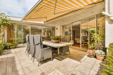 a patio with an umbrella over the dining table and chairs, in front of a large sliding glass door...