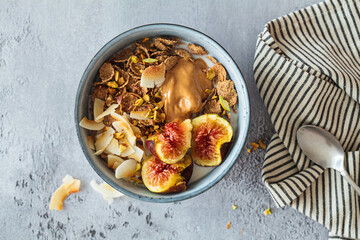 Multigrain breakfast cereals with fig, coconut chips, peanut butter and pistachio. Vegan breakfast concept.