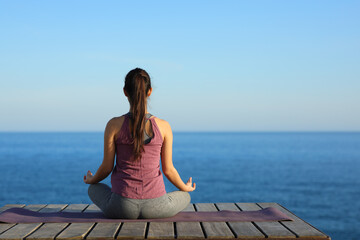 Back view of yogi doing yoga in the coast