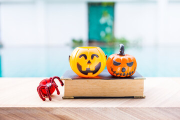 Halloween decoration item on old book with red yarn spider with space on blurred background, outdoor day light, Halloween greeting card background idea