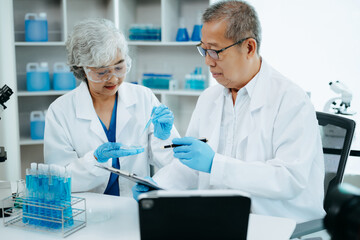 Two scientist or medical technician working, having a medical discuss meeting with Asian senior female scientist supervisor in the laboratory with online reading, test samples and innovation