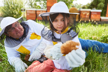 Girl looking at beeswax near senior male beekeeper