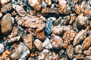 blue, red and brown stones in very clear water of a lake