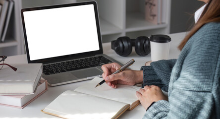 Asian girl watch studying online using applications, app, e learning distance training course at home. Over shoulder view on mockup image on laptop computer with white screen.