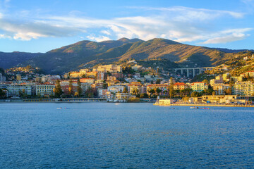 Panoramic view of Sanremo or San Remo from the sea, Italian Riviera, Liguria, Italy. Scenic sunset landscape with city architecture, seafront, mountains, blue water and sky, outdoor travel background - 646761204