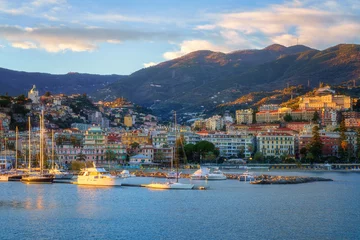 Panoramic view of Sanremo or San Remo from the sea, Italian Riviera, Liguria, Italy. Scenic sunset landscape with city architecture, seafront, mountains, blue water and sky, outdoor travel background © larauhryn