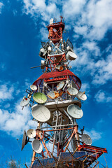 Telecommunication tower with antennas with blue sky in the morning sunlight, on the mountain.