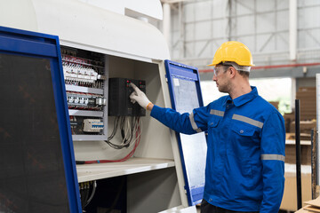 Male electrician engineer maintenance electric system in industry factory. Factory male worker at work in the industry factory, work with CNC machine. Factory engineer male worker maintaining machine