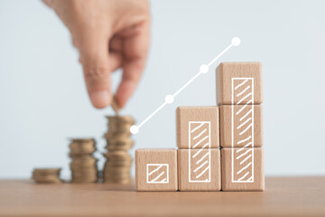 increasing graph bar on wooden cube block with blurred hand putting coins to stacking for money saving profit and business investment growth concept - obrazy, fototapety, plakaty