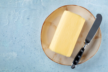 A block of butter with a knife on a plate, shot from above with a place for text