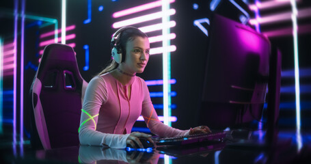 Fototapeta na wymiar Portrait of a Happy Girl Focused on Playing an Online Video Game on a Desktop Computer. Stylish Streamer Playing Games with Internet Players in a Futuristic Neon Studio Room