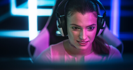 Young Excited Gamer Girl Portrait From Behind the Monitor. Stylish Young Female with Striking Make Up Playing and Streaming Online Video Games From a Bright Neon Room © Gorodenkoff