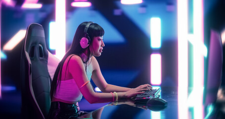 Japanese Female Gamer Playing Online Video Game on Computer. Portrait of an Excited Woman in Headphones Battling in PvP Tournament with Other Players, Talking with Team on Microphone