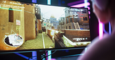 Close Up of a Female Gamer Girl Playing First-Person Shooter Online Video Game on a Computer. Focus Switching From Hands Using Keyboard to the Desktop Display. Streamer Sitting in a Neon Studio Room © Gorodenkoff